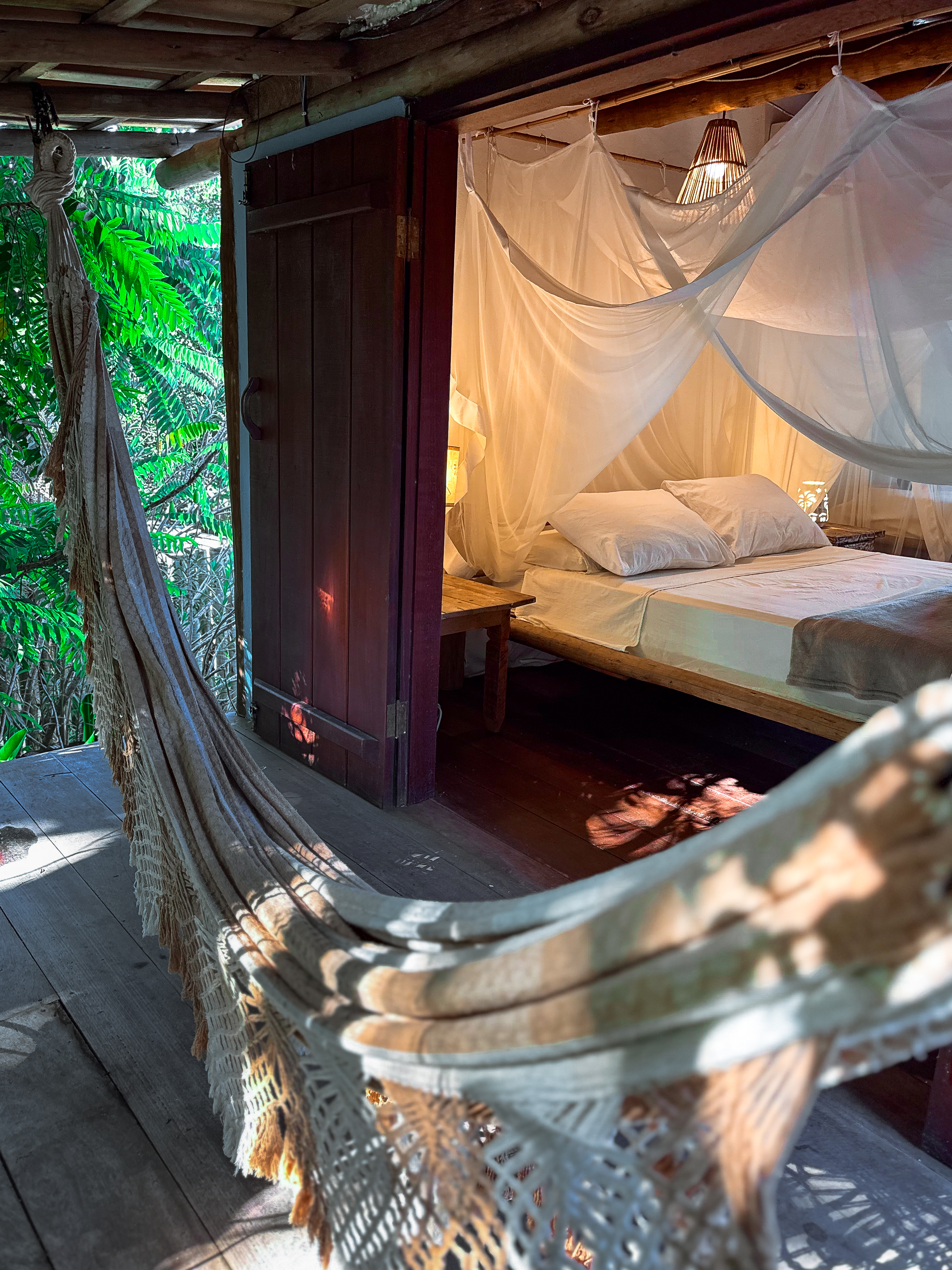 Suíte Casa Aratu com cama, mosquiteiro e rede na varanda