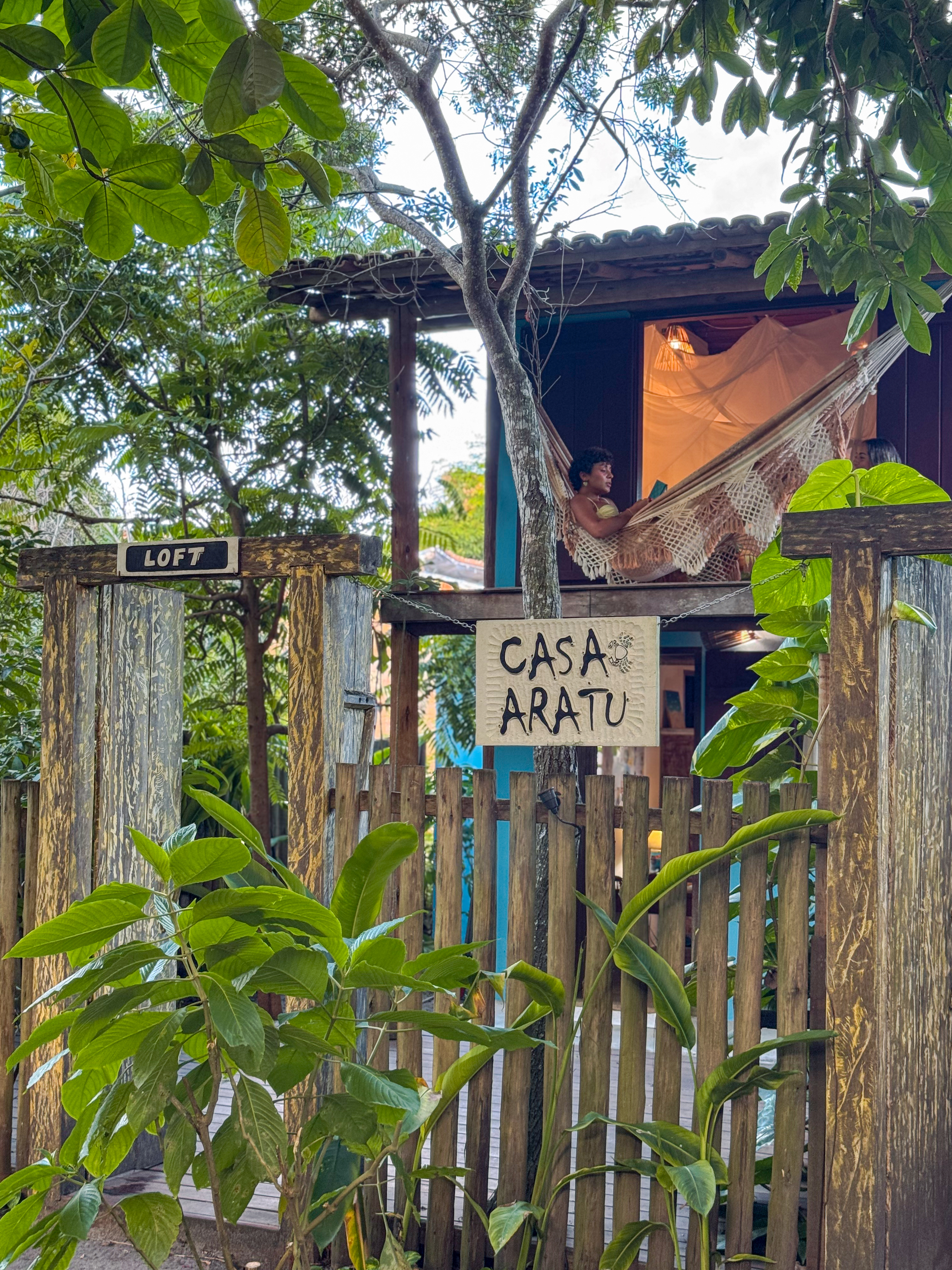 Entrada da Casa Aratu — loft com rede entre as árvores