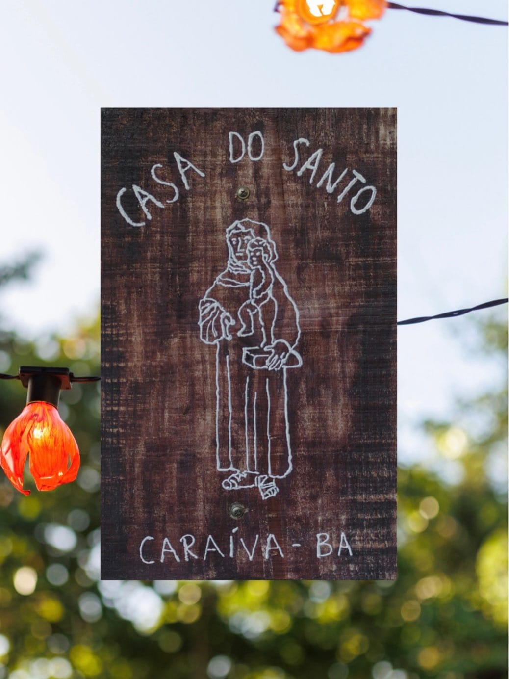 Placa de madeira da Casa do Santo entre luzes